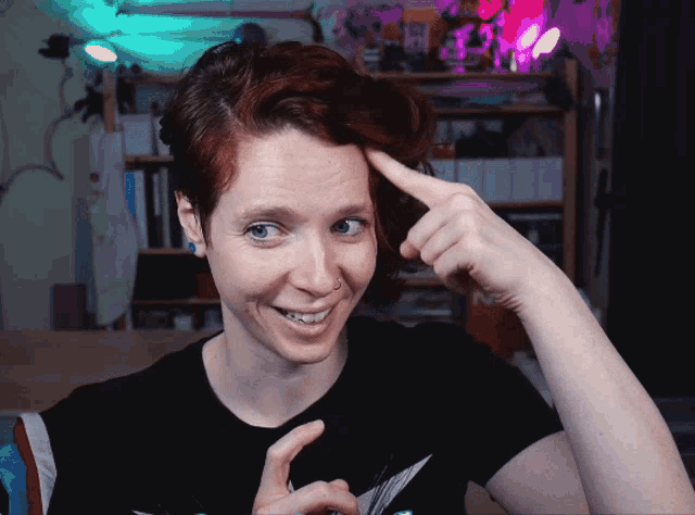 a woman with red hair is smiling and pointing at her head