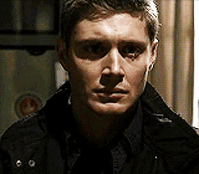 a man in a black jacket is looking at the camera .