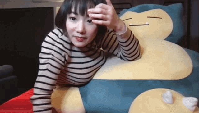 a woman in a striped shirt is laying on a giant stuffed animal .