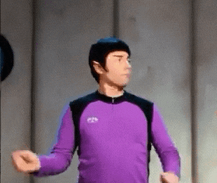 a man in a purple shirt is standing in a room with his arms outstretched