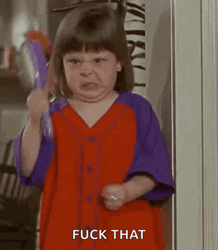 a little girl in a red and purple dress is brushing her hair and making an angry face .