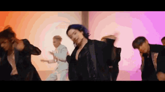 a woman with blue hair is dancing with a group of men in a room .
