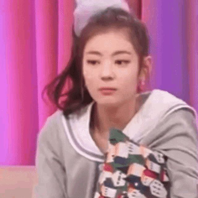 a girl in a sailor suit is sitting on a couch and making a face .