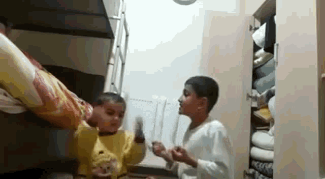 two young boys are playing in a bedroom with a bed and a closet .