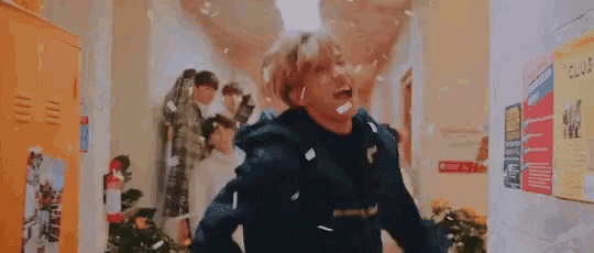 a group of people are standing in a hallway with confetti falling around them .