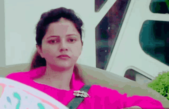 a woman in a pink shirt with a brooch on her neck