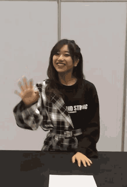 a woman wearing a black shirt that says and string is sitting at a table