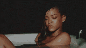 a naked woman is laying in a bathtub with her legs crossed .
