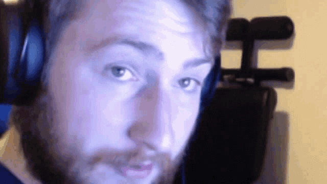 a man with a beard is wearing headphones and making a funny face