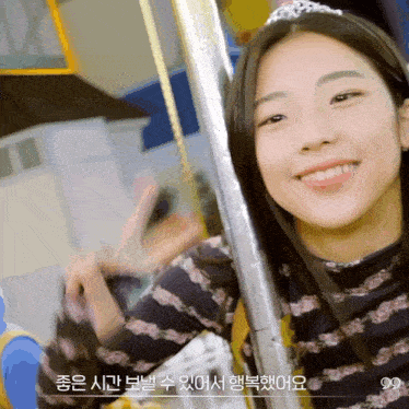 a girl wearing a tiara is smiling and giving the peace sign