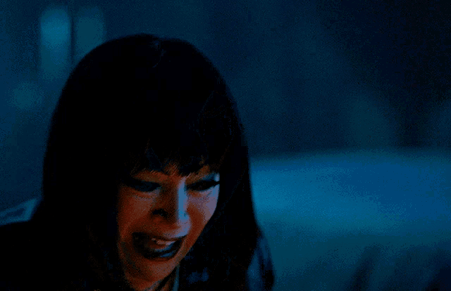 a woman in a dark room with a tear running down her face