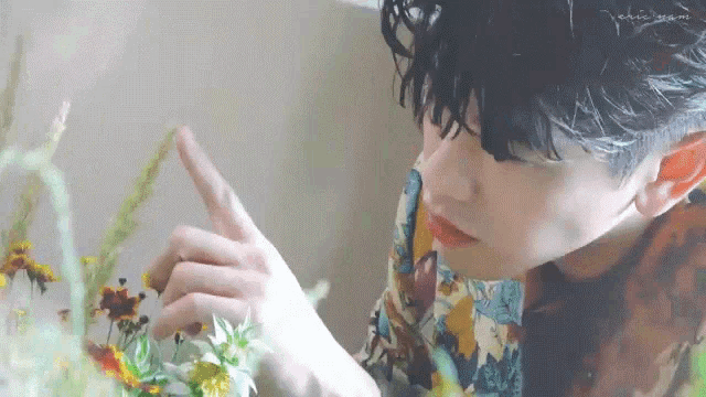 a young man is looking at a bunch of flowers .