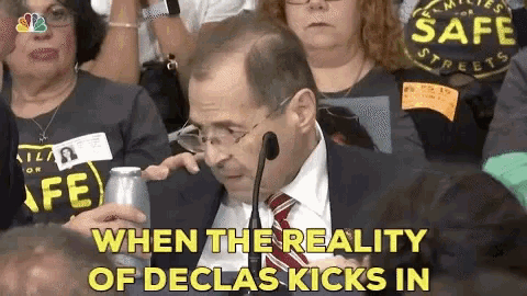 a man in a suit and tie sitting in front of a microphone with the words " when the reality of declas kicks in "