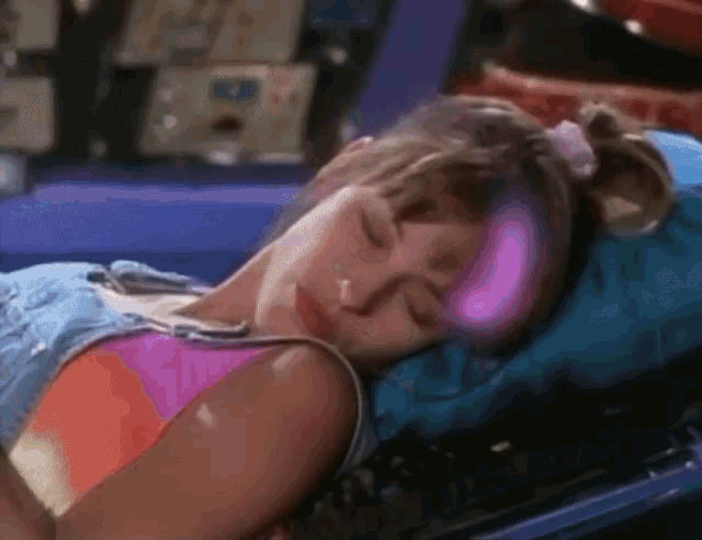 a woman is laying on a bed with her eyes closed and her head is glowing pink .