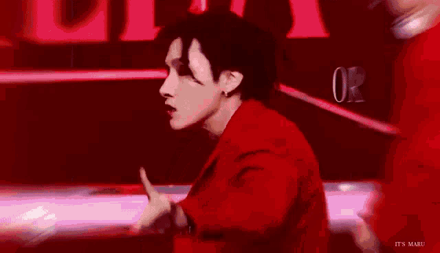 a man is standing in front of a window in a room with a red light coming out of it .