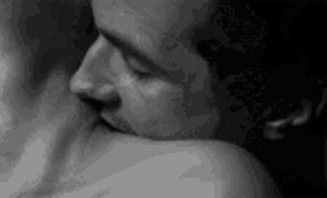 a black and white photo of a man kissing a woman .