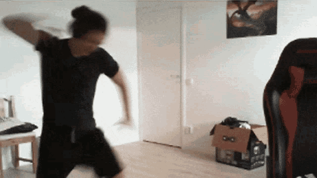 a man in a black shirt is dancing in a room with a picture of a dragon on the wall behind him