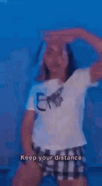 a woman in a white shirt and plaid shorts is dancing in a dark room .