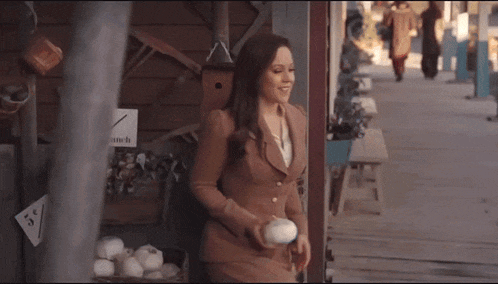a woman in a brown suit holds a white ball in her hand
