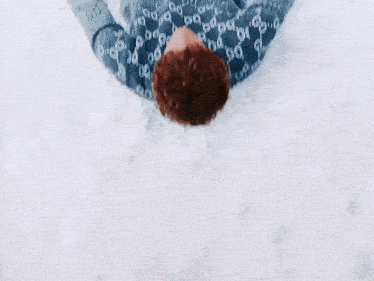 a person wearing a gucci sweater is laying down in the snow