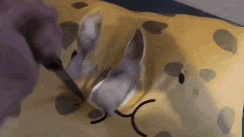 a cat is laying on a yellow pillow with a knife .