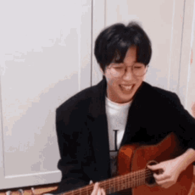 a young man is playing a guitar and smiling .