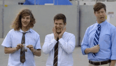 three men in suits and ties are standing next to each other and one of them is making a funny face .