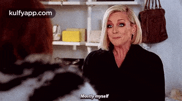 a woman in a black jacket is talking to another woman in a room .