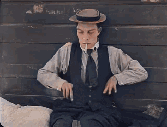 a man in a hat sits on a bench with a pillow