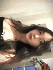 a woman with long black hair is taking a selfie with a tiktok app on her phone .
