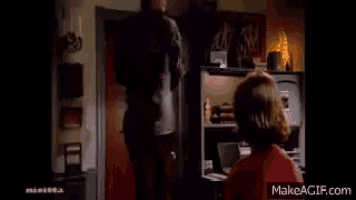 a woman in a red shirt is standing next to a man in a brown shirt in a living room ..