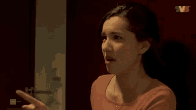 a woman in a red shirt is standing in front of a tv screen