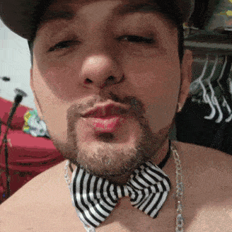 a man with a beard wearing a striped bow tie and chain around his neck
