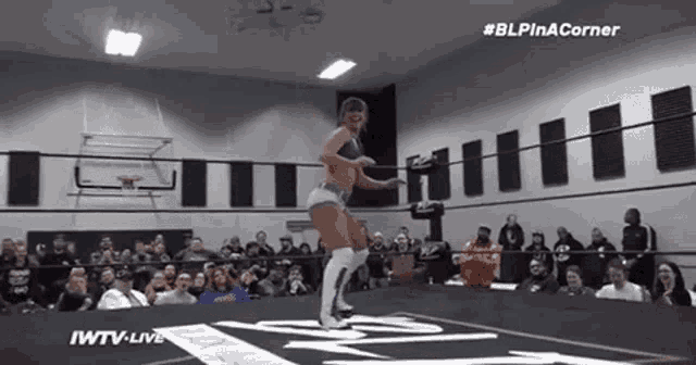 a woman is dancing in a wrestling ring in front of a crowd of people .