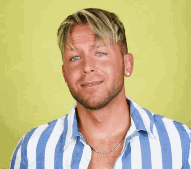 a man wearing a blue and white striped shirt with a necklace around his neck