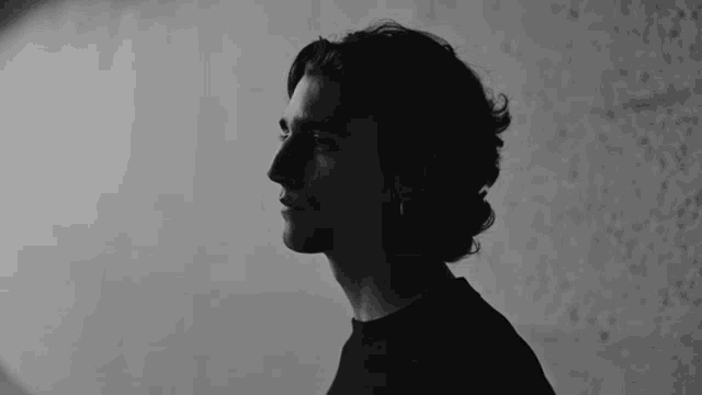 a black and white photo of a man wearing a black shirt and earrings