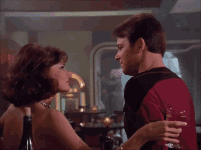 a man and a woman are looking at each other in a room