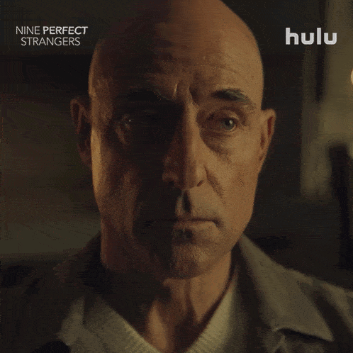a close up of a man 's face with the words nine perfect strangers on the bottom