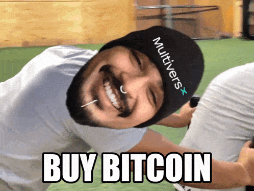 a man wearing a hat that says multivers on it is smiling and says buy bitcoin