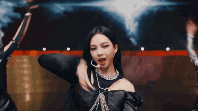 a close up of a woman wearing a black top and a silver chain around her neck