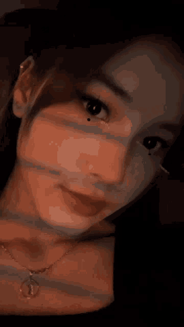 a close up of a woman 's face with a necklace and earrings .