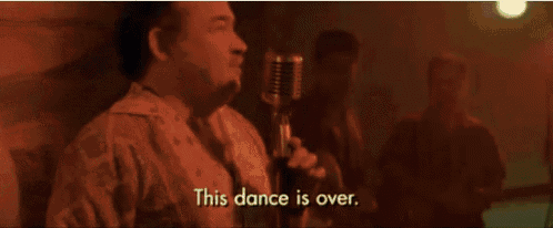 a man is singing into a microphone in a dark room in front of a group of people .