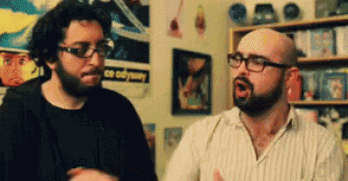 two men talking in front of a poster that says odyssey on it