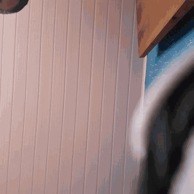 a close up of a pink wall with a wooden shelf on it