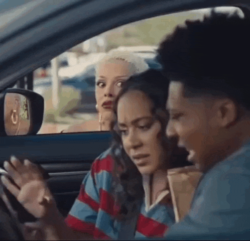a man and a woman are sitting in a car looking out the window .