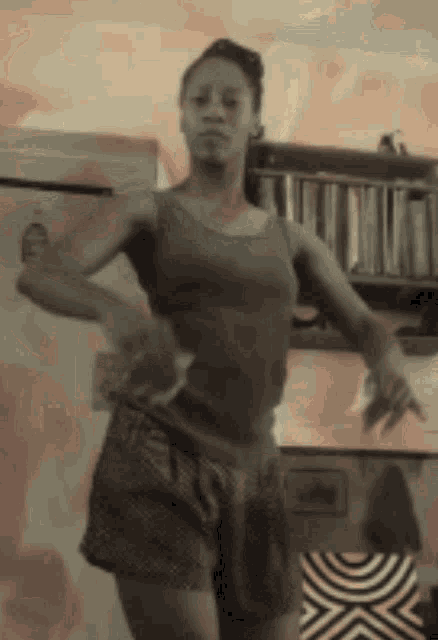 a woman in a tank top and shorts is dancing in the kitchen .