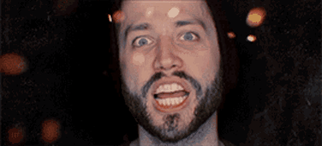 a man with a beard is smiling with a tattoo on his forehead