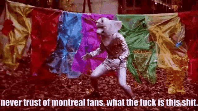 a clown is dancing in front of a banner that says never trust of montreal fans what the fuck is this shit ..