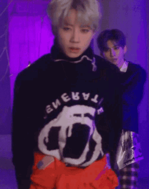 a man wearing a black sweater with the word energy on it is standing next to another man