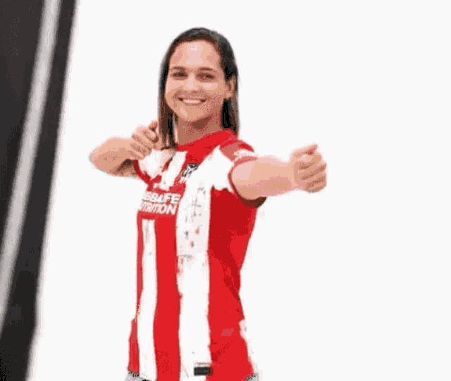 a woman in a red and white striped shirt is giving a thumbs up